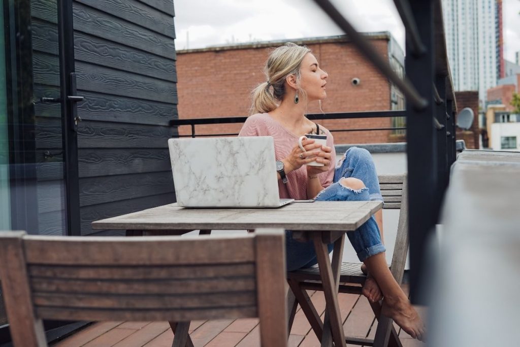 a girl sitting at her laptop outside drinking coffee: how to find contentment in every season