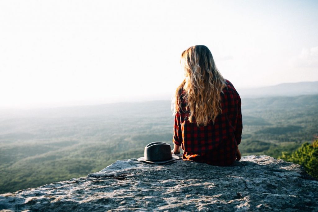 woman sitting on a rock with a view of mountains in the distance