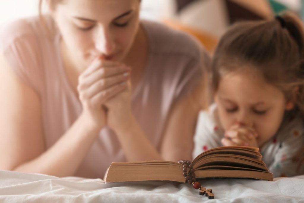 mom praying with her daughter