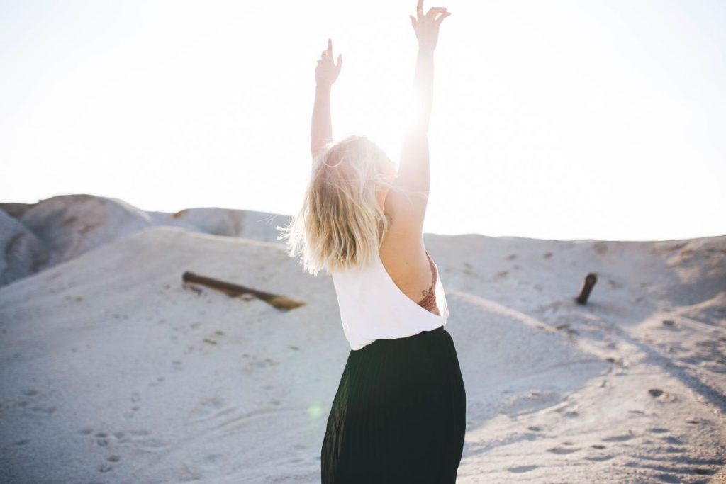 I was blind but now i see: a woman standing in the desert with her arms raised, praising God