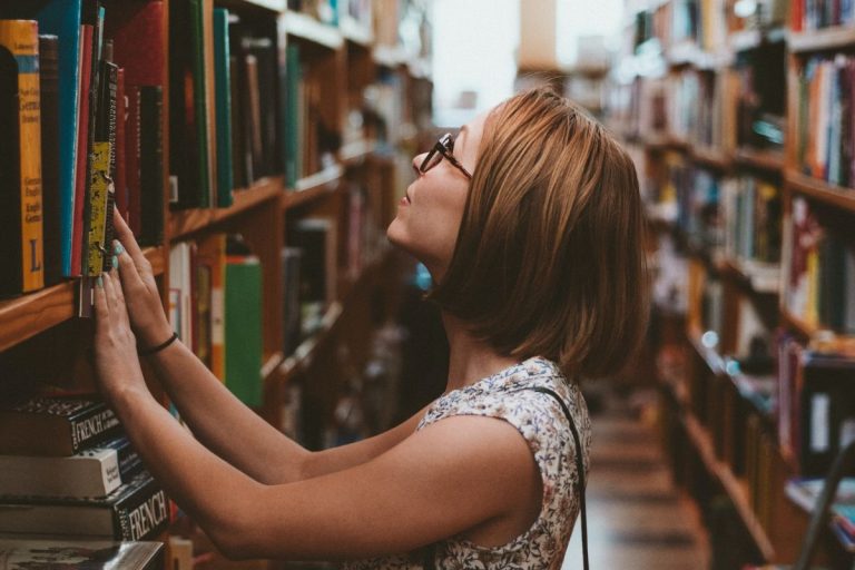 a woman searching for a book in a library
