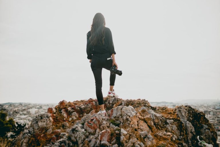 God Sees and Knows everything Salt and Sparrow, woman standing on a hillside with a camera in her hand staring off in the distance