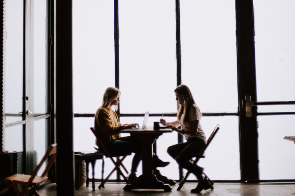 two women sitting at a cafe table together
