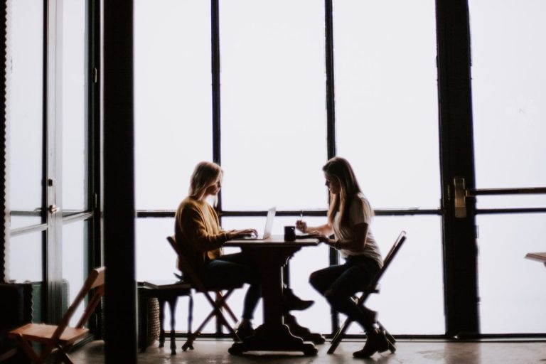 two women sitting at a cafe table together