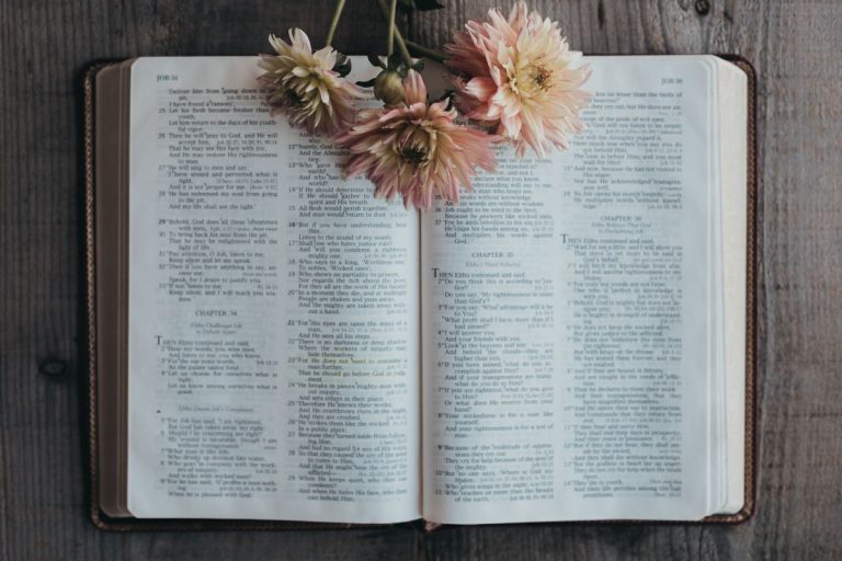 Bible sitting open on a table with flowers on the pages