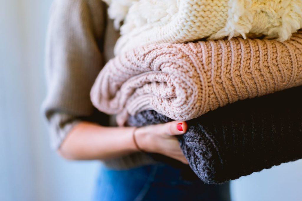 woman carrying folded quilts and blankets
