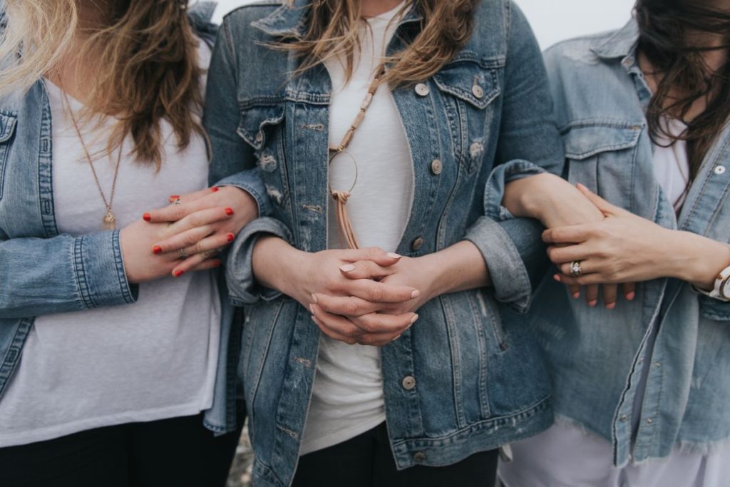 Three women standing with arms linked