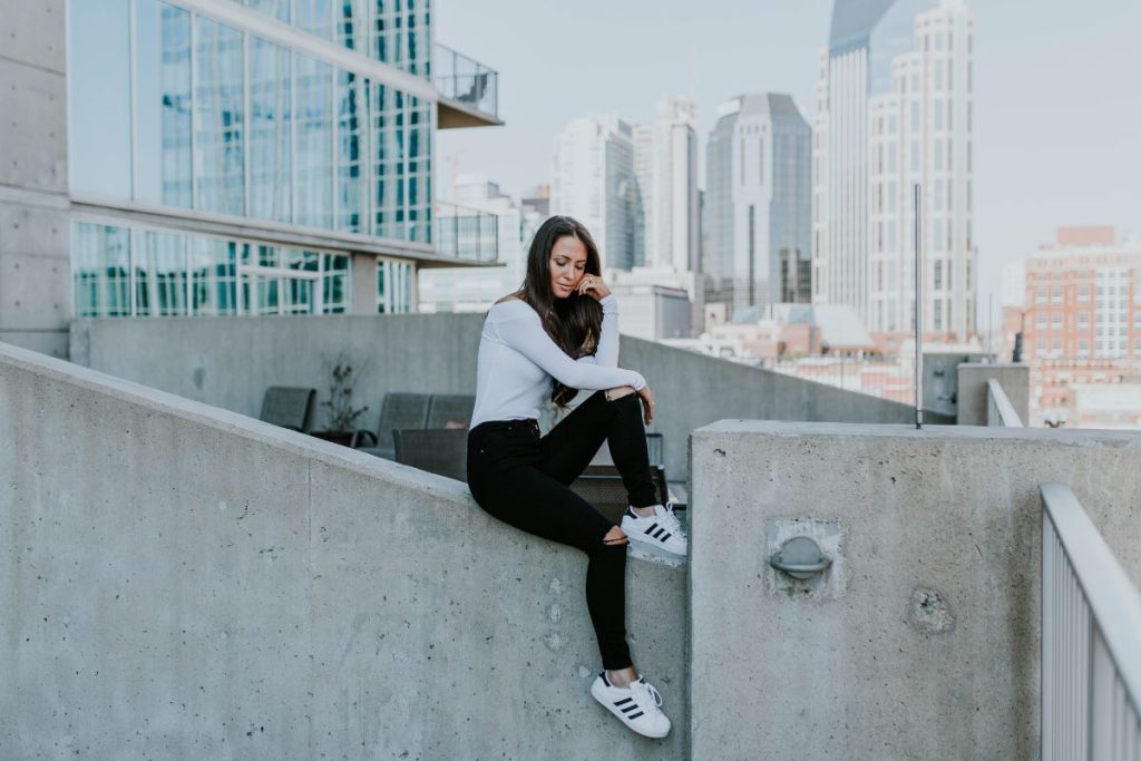woman feeling defeated, sitting on top of a stone wall downtown