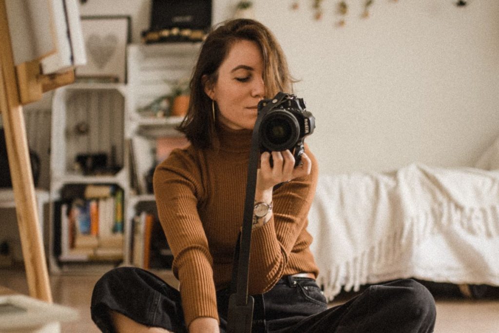 a woman holding a camera taking a selfie in the mirror