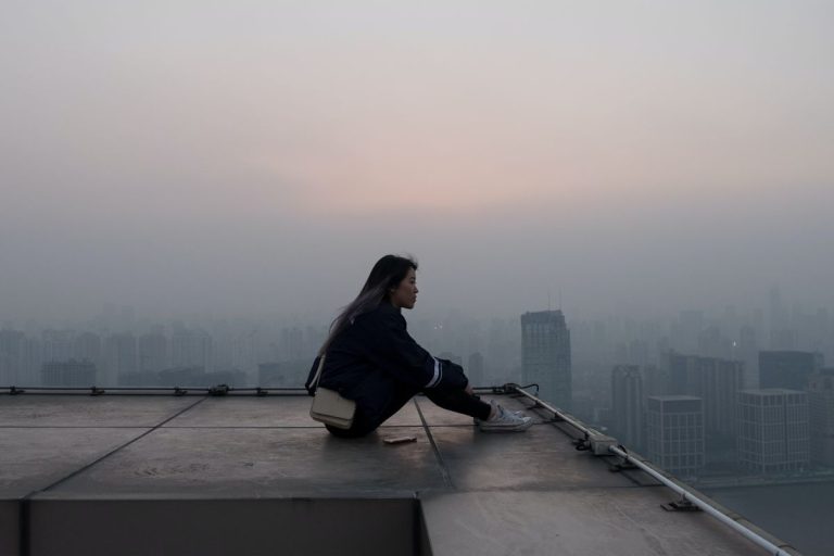 a woman sitting on a rooftop staring out over the city