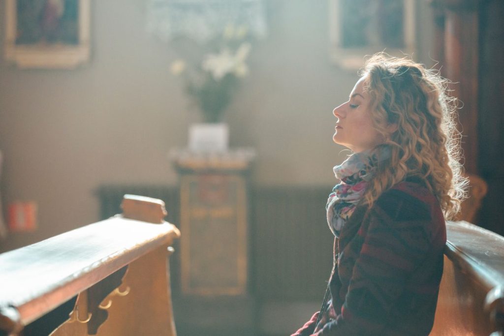 woman sitting in a church pew praying