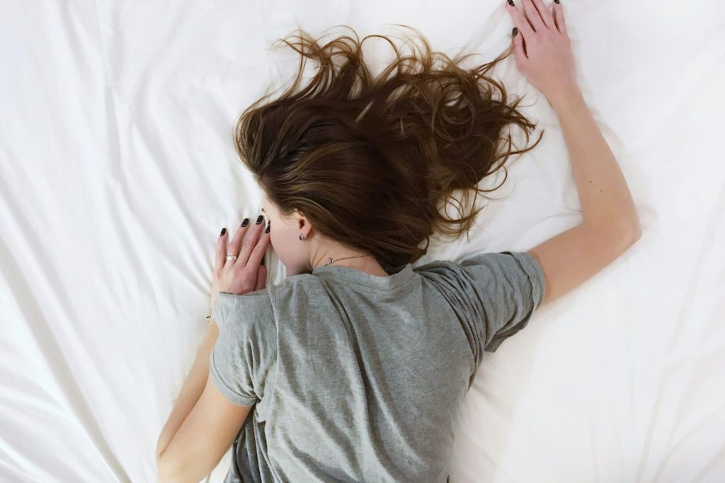 a woman sleeping in bed, she's on her stomach and her dark hair is fanned out around her head