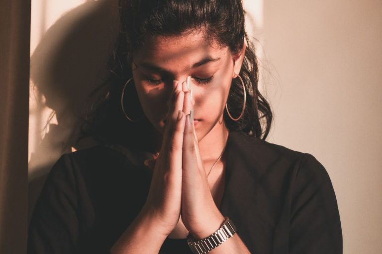 a woman with her eyes closed and her hands brought together in prayer in front of her face