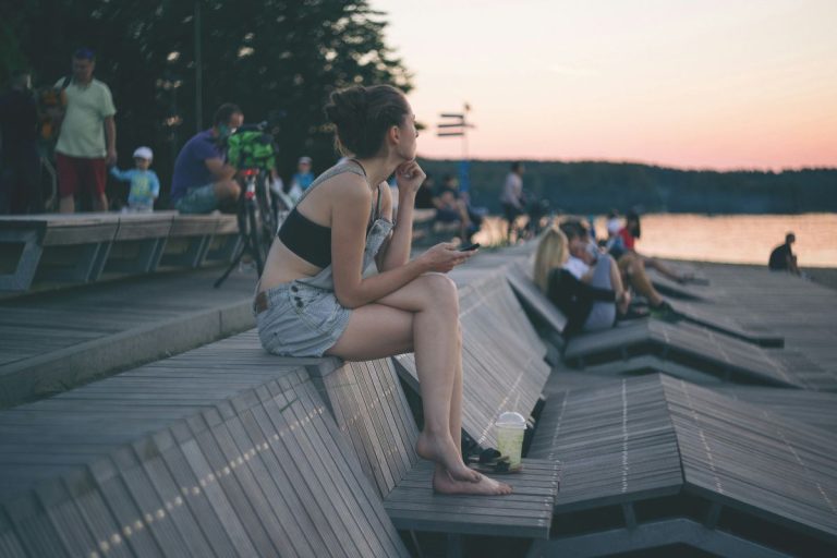a girl sitting by herself while there are groups of people around