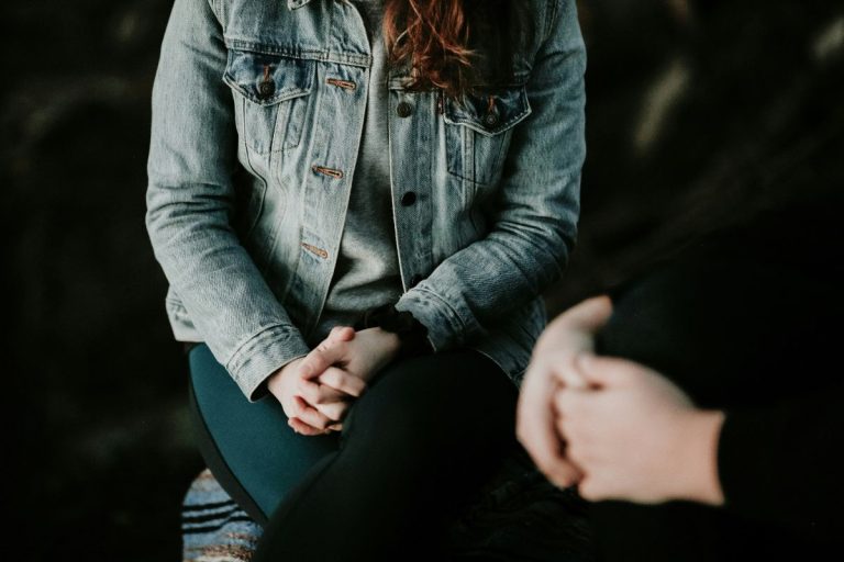 two people sitting with their hands clasped in their laps