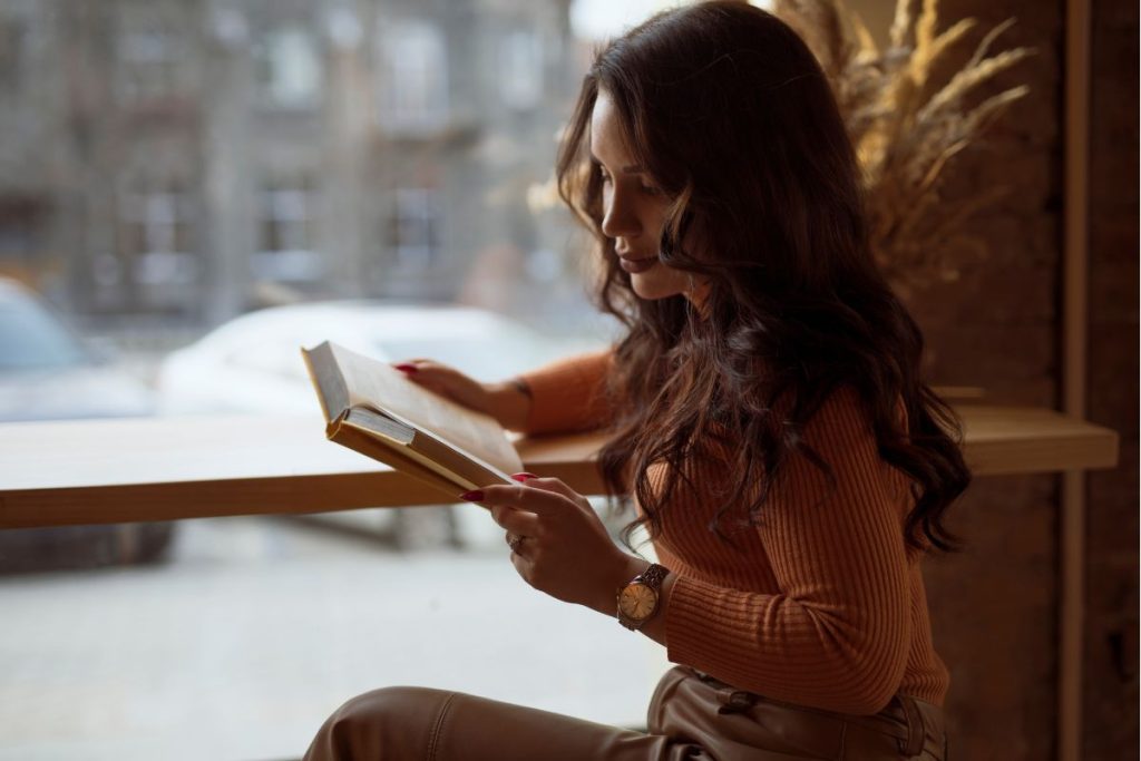 a woman sitting in a coffee shop reading a book