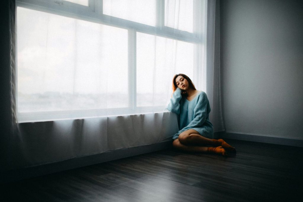 a woman sitting by the window with her head in her hands