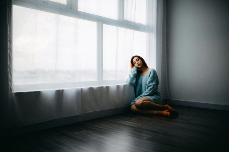a woman sitting by the window with her head in her hands