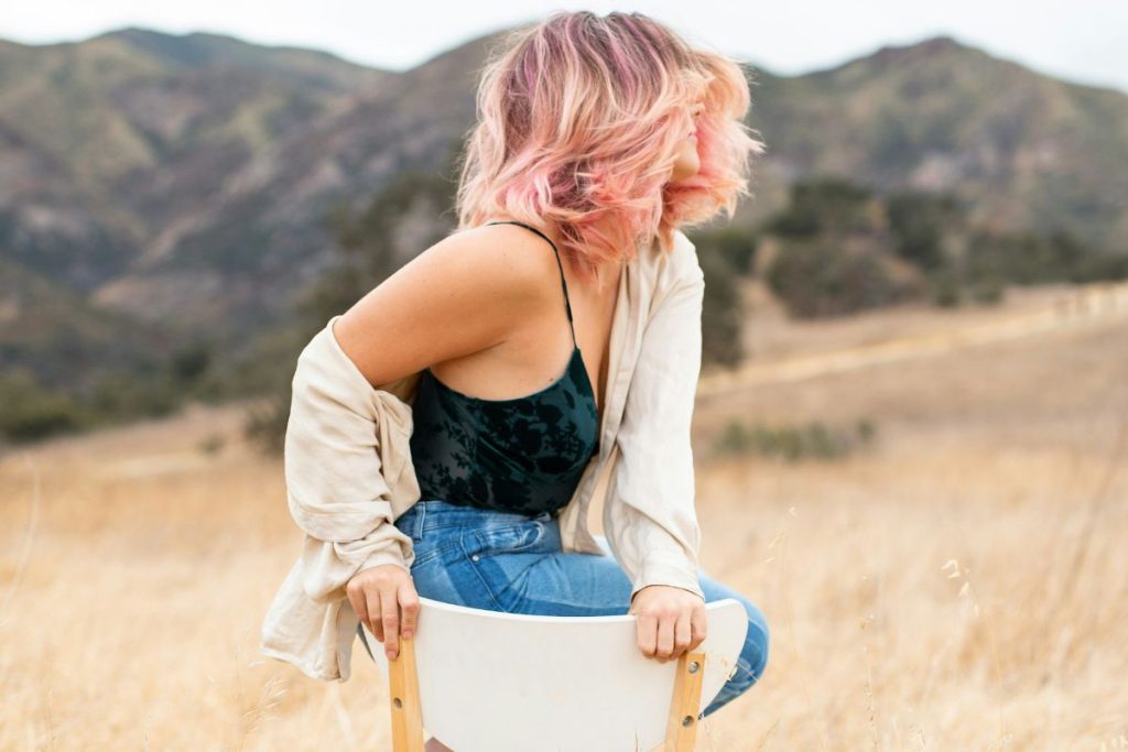 a girl sitting on a chair in the middle of a field