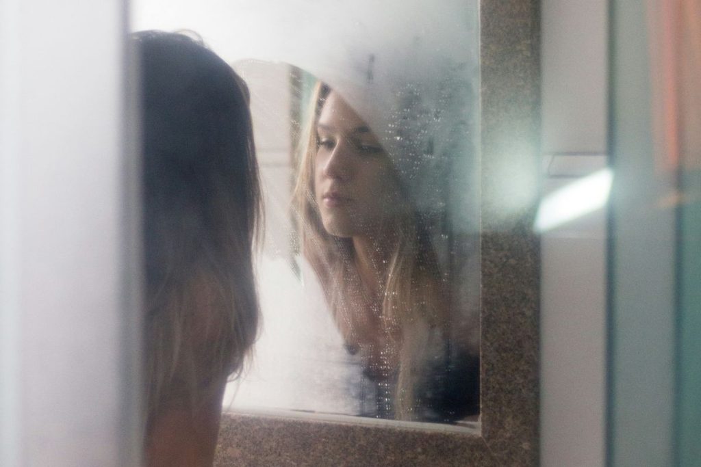 Young woman staring at her reflection in a mirror