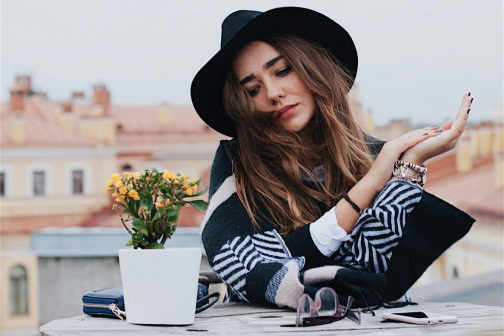 a woman with long brown hair wearing a trendy hat