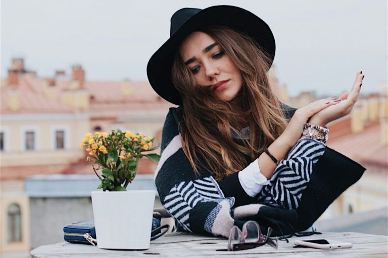 a woman with long brown hair wearing a trendy hat