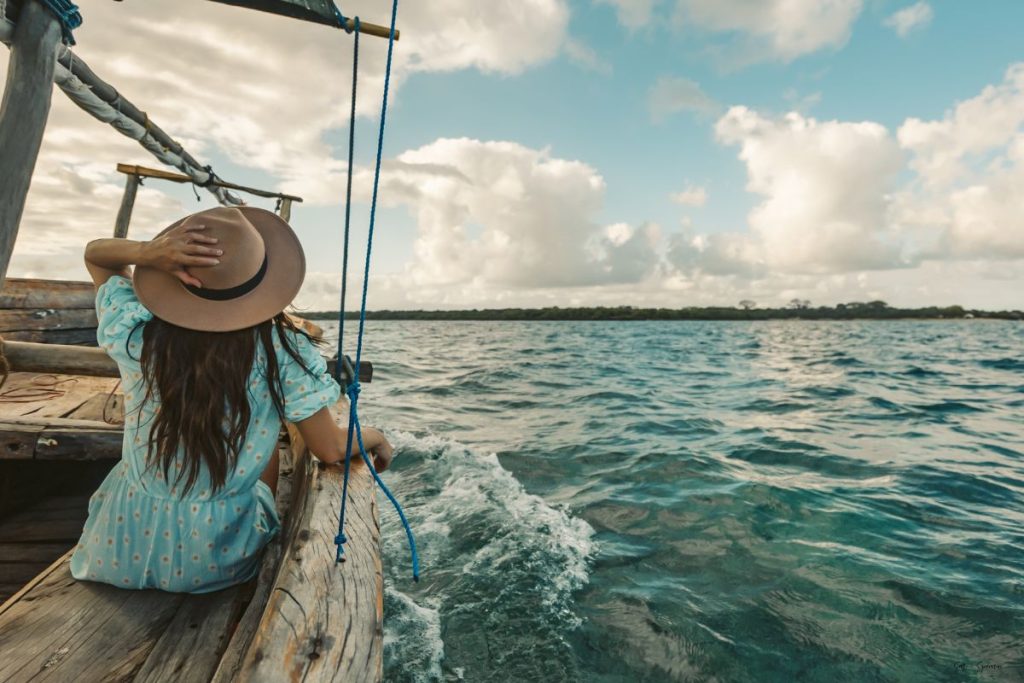 a woman sitting alone on a boat out in the middle of the ocean