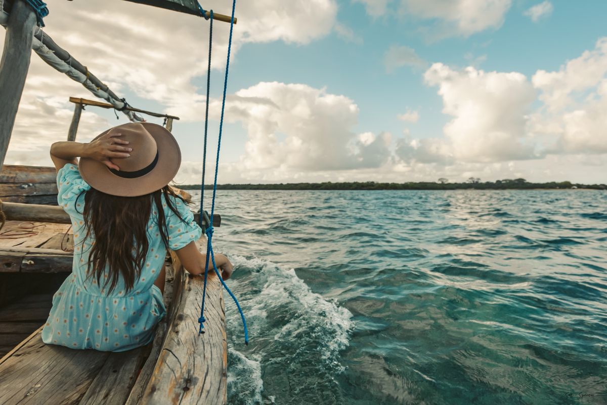 a woman sitting alone on a boat out in the middle of the ocean