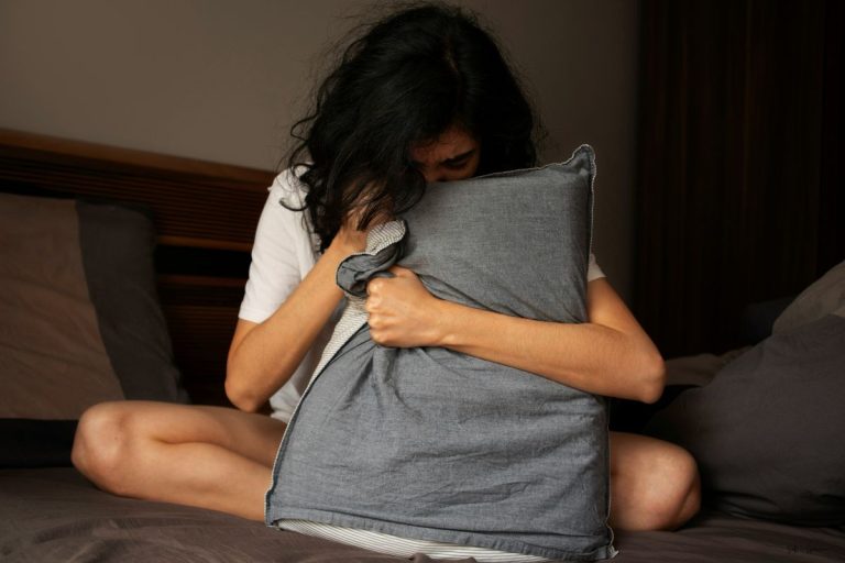 a woman holding her pillow while she has a panic attack
