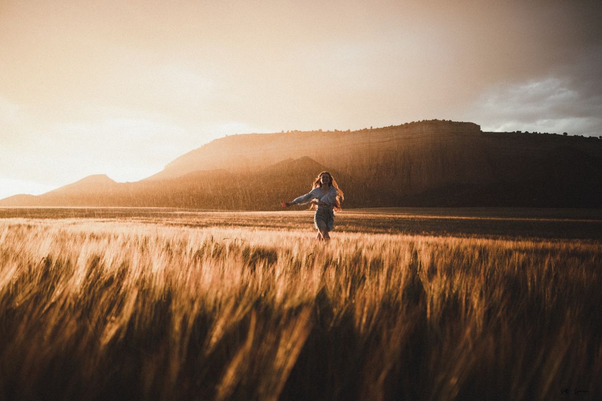 a woman running through a field at sunset