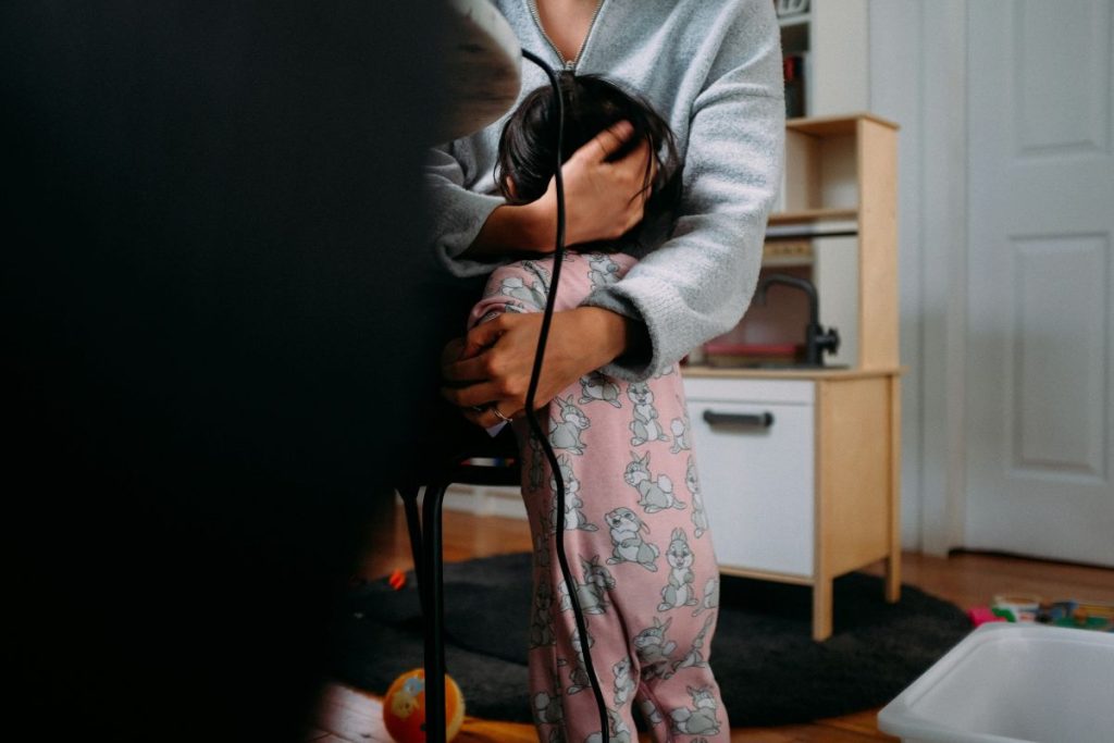 a mom leaning down and hugging her child to her chest