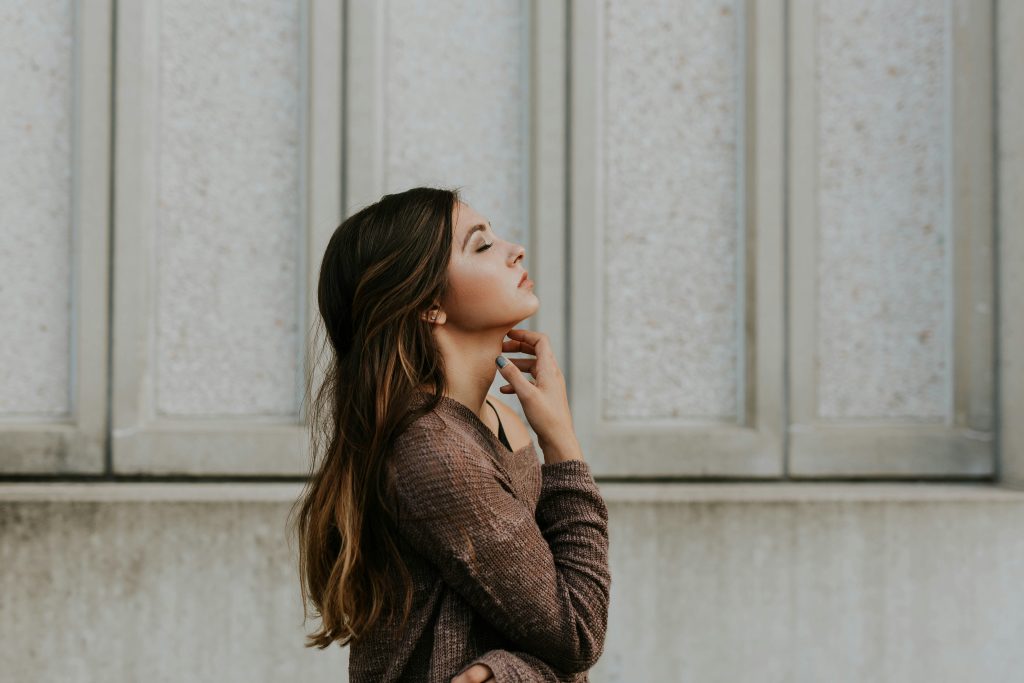 a young woman standing with her eyes closed as if in thought