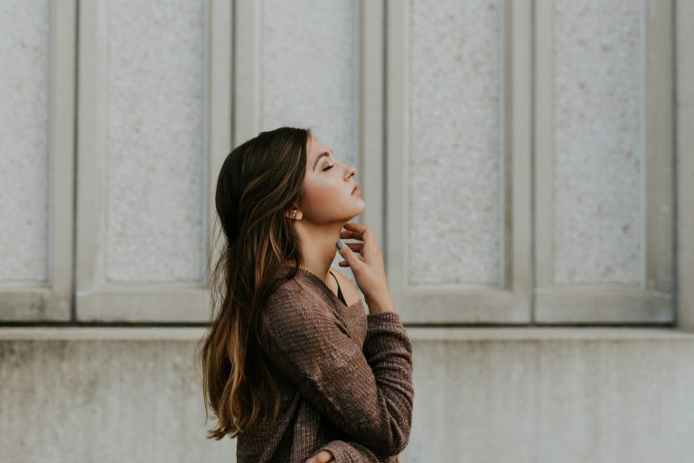 a young woman standing with her eyes closed as if in thought