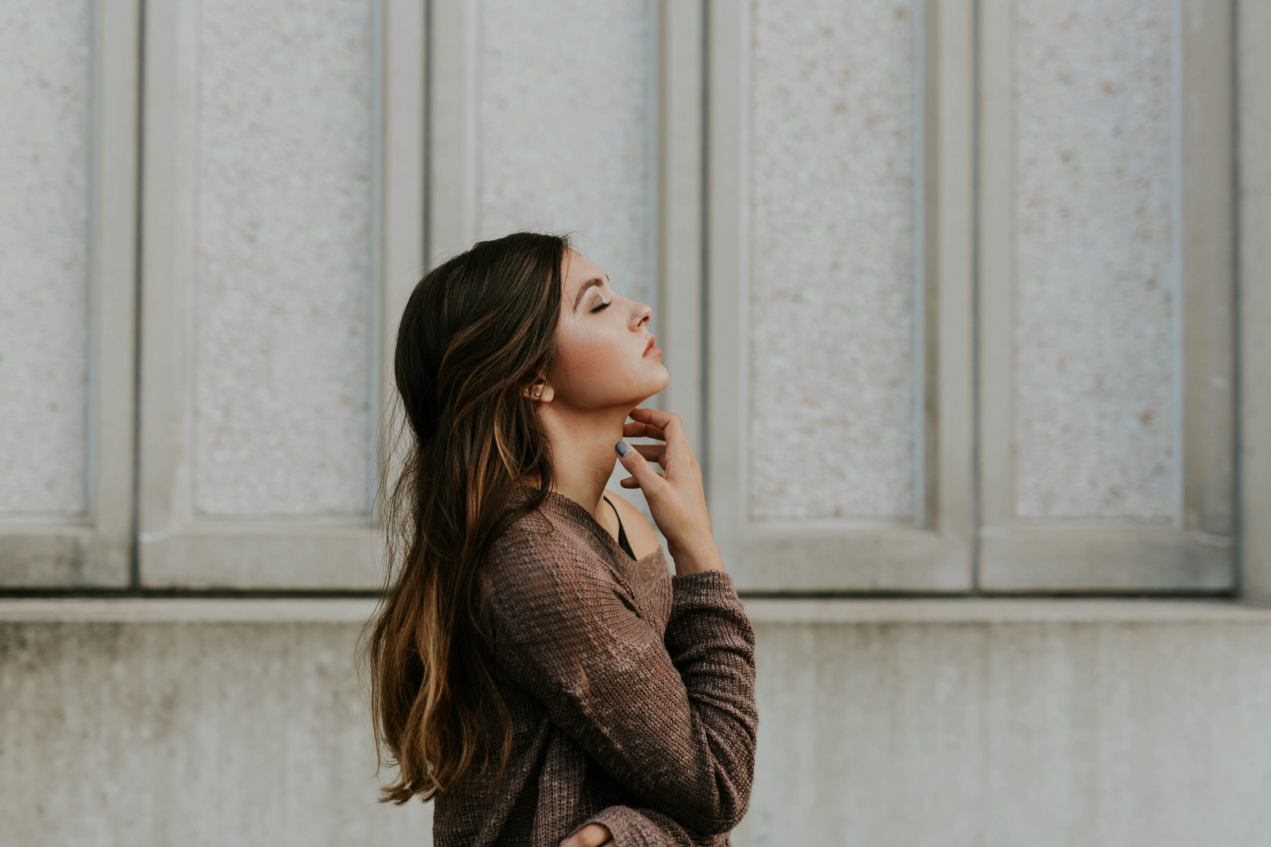 a young woman standing with her eyes closed as if in thought