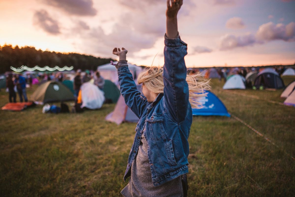 a woman dancing outside at what appears to be a campground or festival
