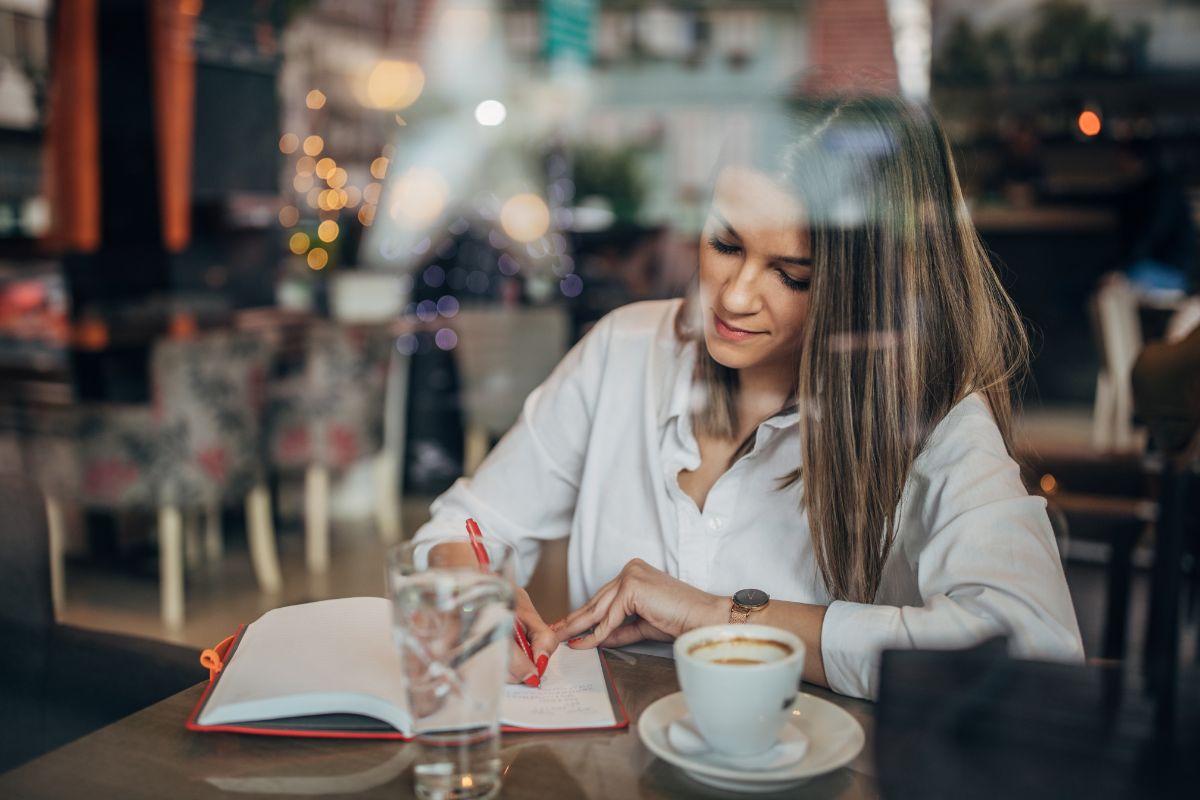 woman sitting at coffee shop writing in her journal
