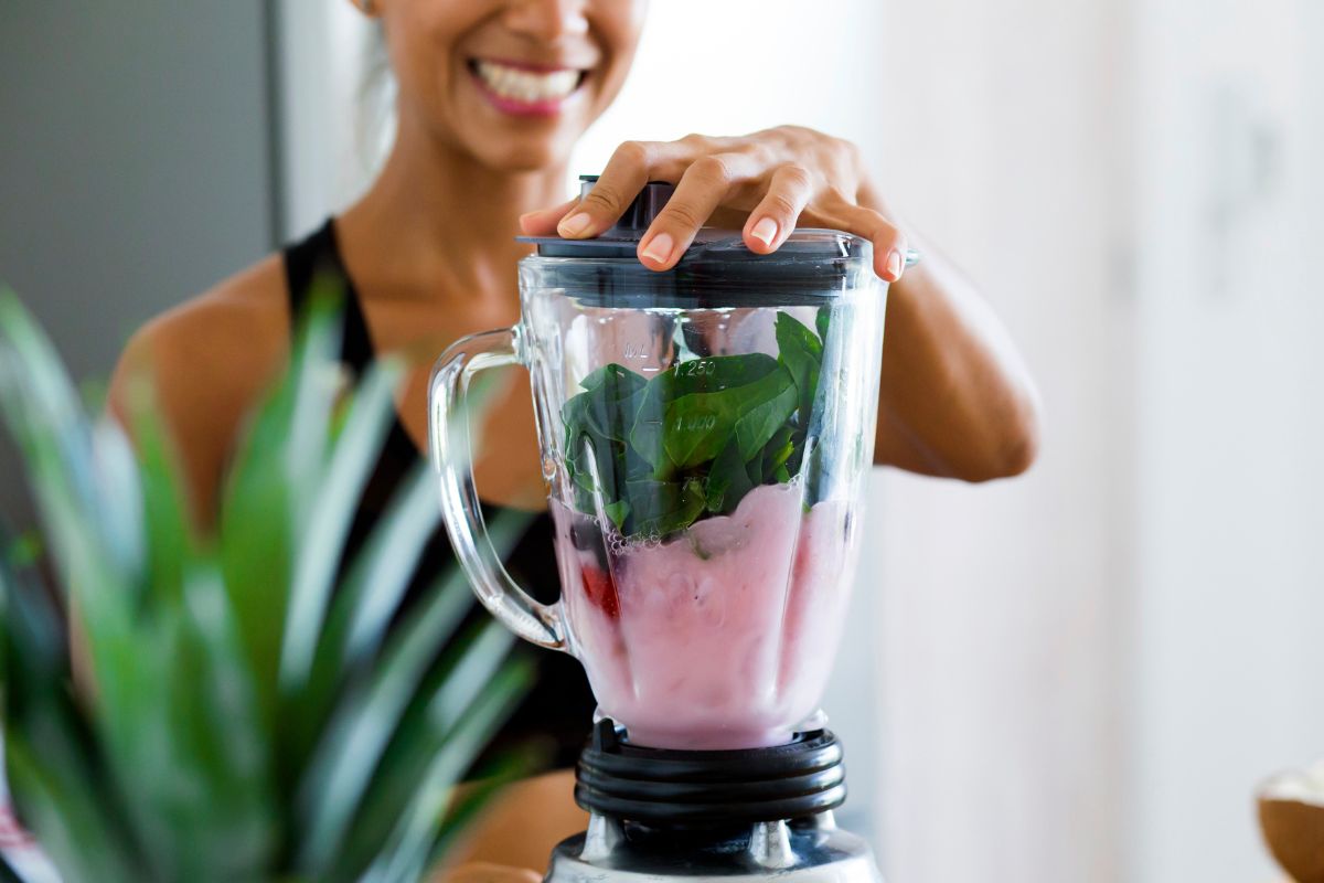 woman blending a smoothie with fruit and vegetables