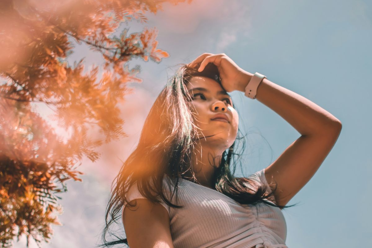 a woman standing outside underneath a beautiful tree and a clear blue sky